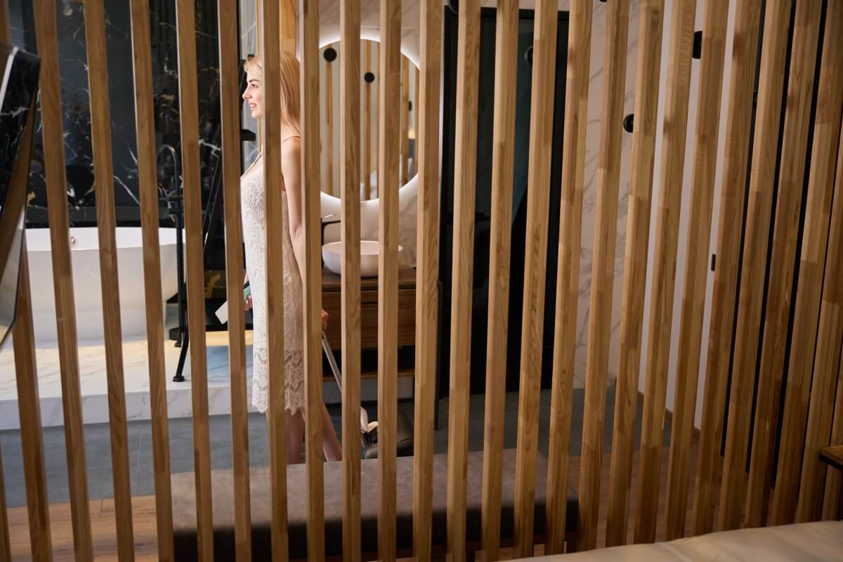 Eine Frau steht hinter dekorativen Holzelementen, die an Seitenwände für Gartenlauben erinnern.