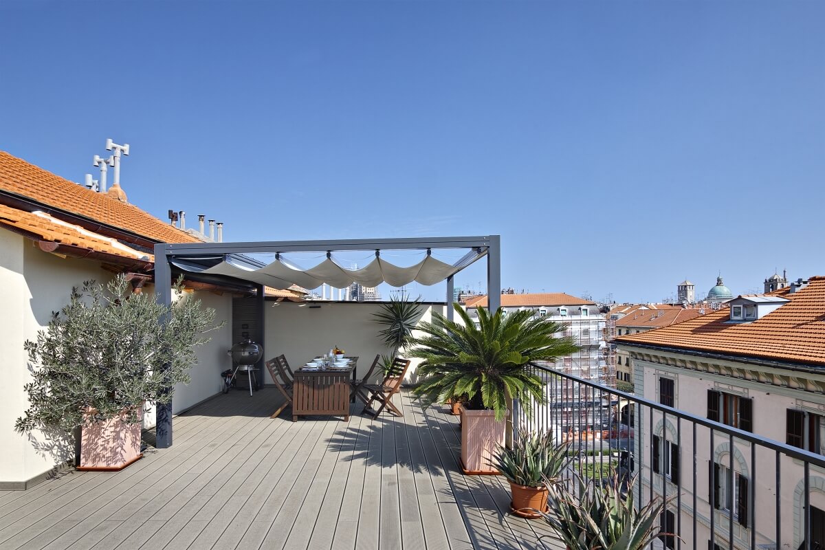 Eine Dachterrasse mit Sitzbereich und Verschalungen aus beweglichen Holzlamellen bietet Blick auf die Stadt.