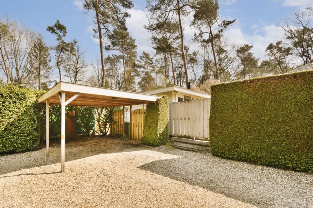 W ogrodzie znajduje się zadaszenie z zabudowy z drewnianych desek otoczone żywopłotem.